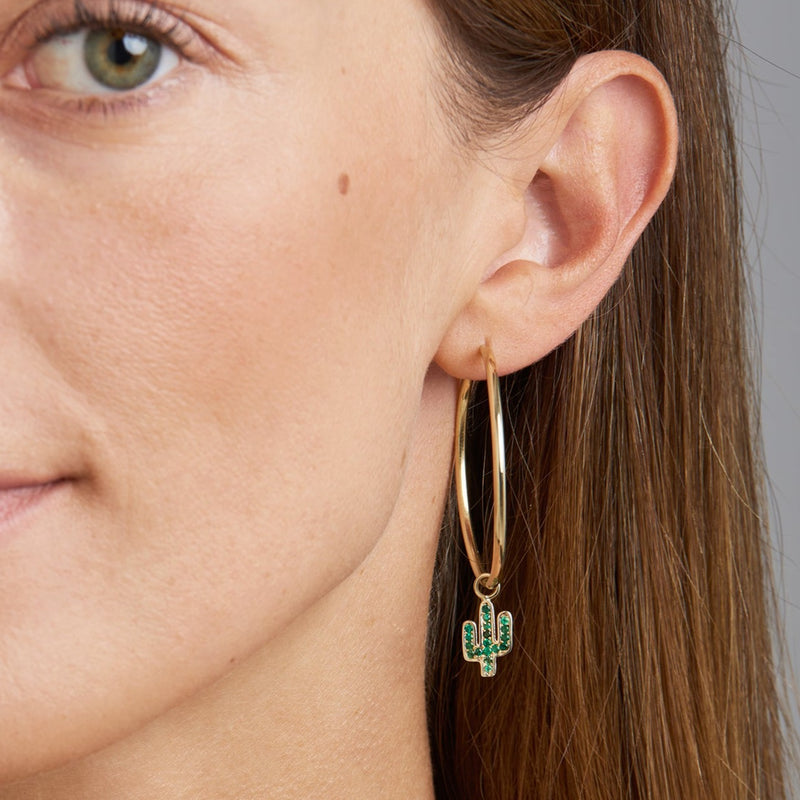 Our two piece 14 karat gold hoop earrings feature the Cactus Charms with handset emerald stones. The two charms are different and add a playful and unique look to your eargame. Take off the charm and wear the essential hoops on its own. 